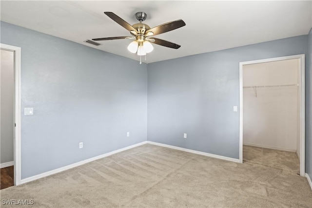 unfurnished bedroom featuring a closet, visible vents, a spacious closet, carpet flooring, and baseboards