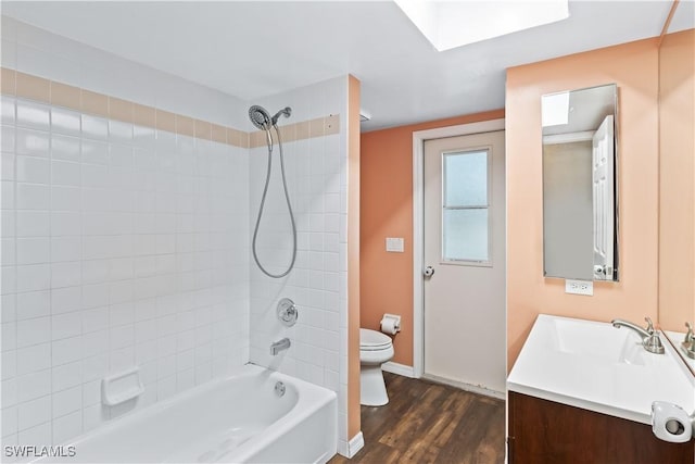 bathroom with bathtub / shower combination, toilet, vanity, wood finished floors, and baseboards