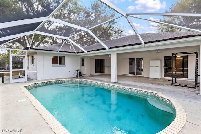 pool with a patio area, ceiling fan, and glass enclosure