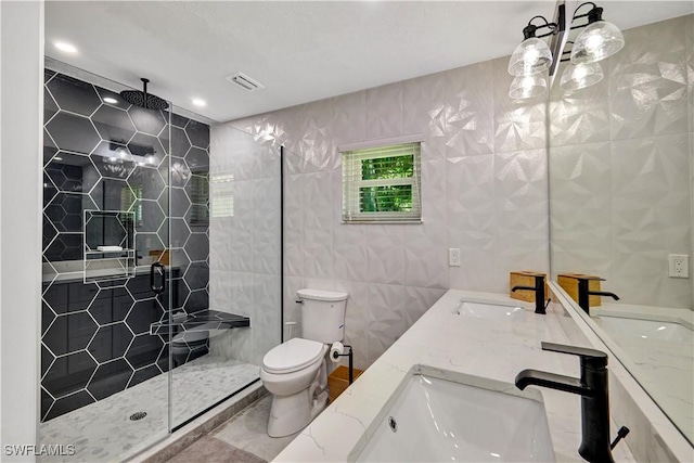 bathroom featuring a shower stall, a sink, visible vents, and tile walls