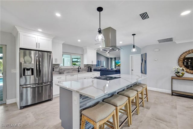 kitchen with cooktop, visible vents, light stone counters, and stainless steel fridge with ice dispenser