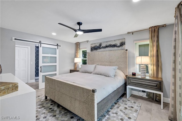 bedroom with a closet, ceiling fan, baseboards, and a barn door