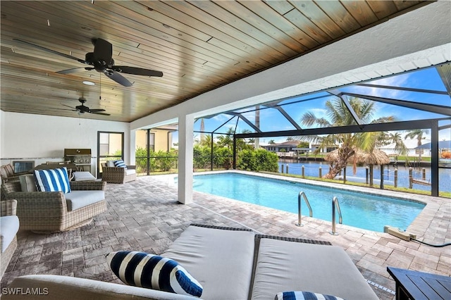 pool with a patio, a lanai, a water view, exterior kitchen, and an outdoor living space