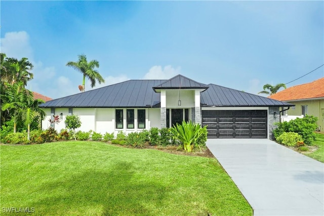 view of front of home featuring driveway, metal roof, an attached garage, a standing seam roof, and a front yard