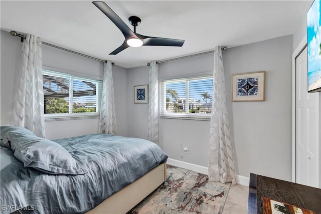 bedroom featuring multiple windows, a ceiling fan, and baseboards