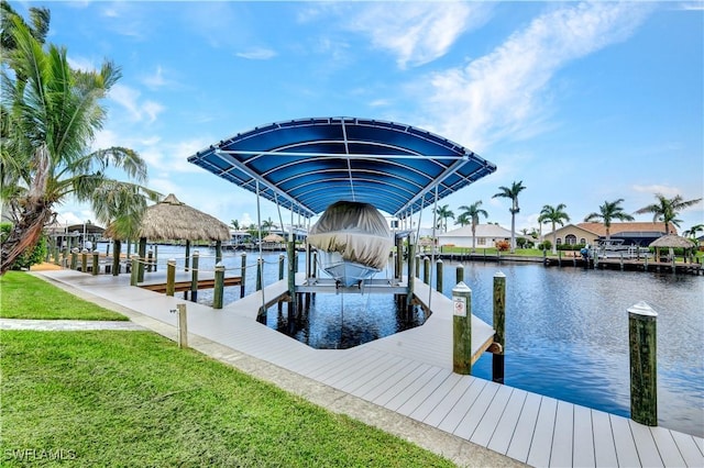 dock area featuring a water view, boat lift, and a lawn