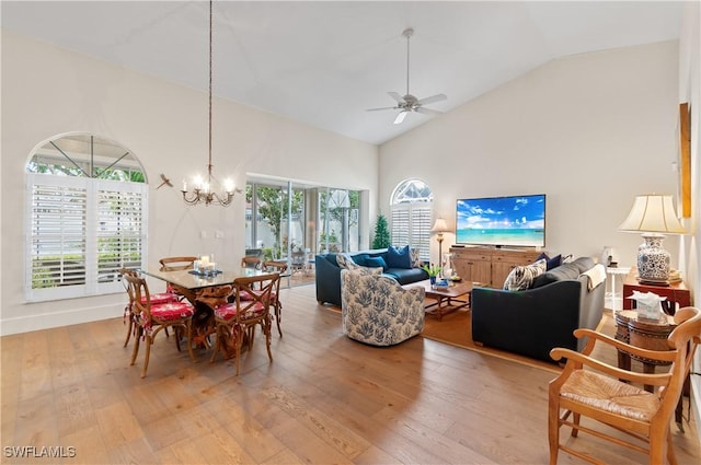 dining area with ceiling fan with notable chandelier, high vaulted ceiling, and light wood finished floors