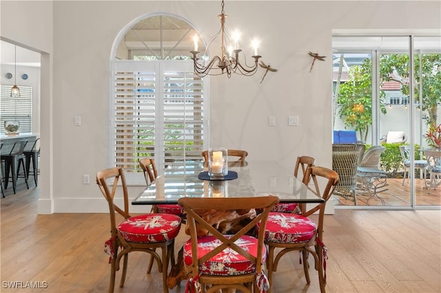 dining space featuring baseboards, an inviting chandelier, and wood finished floors