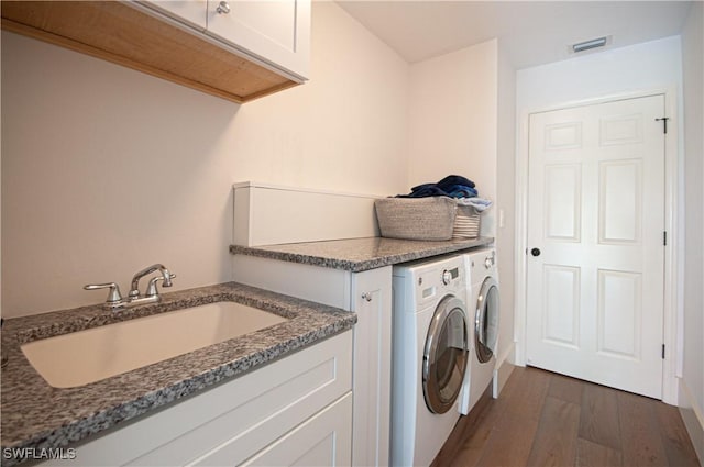 washroom with visible vents, dark wood-type flooring, separate washer and dryer, cabinet space, and a sink