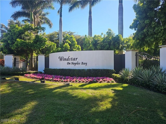 community / neighborhood sign with a lawn and fence