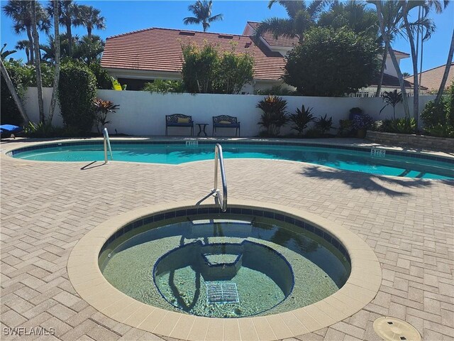 view of pool with an in ground hot tub, a fenced in pool, a fenced backyard, and a patio