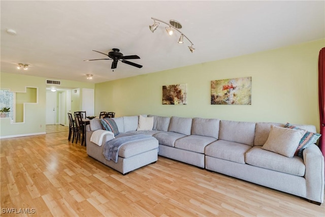 living area with a ceiling fan, visible vents, light wood finished floors, and baseboards