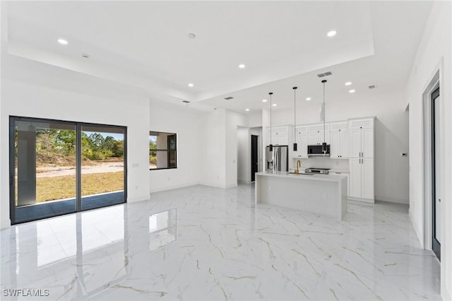 kitchen with stainless steel appliances, visible vents, open floor plan, marble finish floor, and a tray ceiling