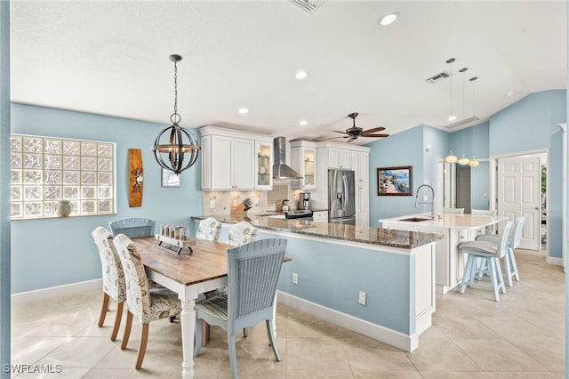 dining space featuring ceiling fan with notable chandelier, lofted ceiling, visible vents, and light tile patterned floors