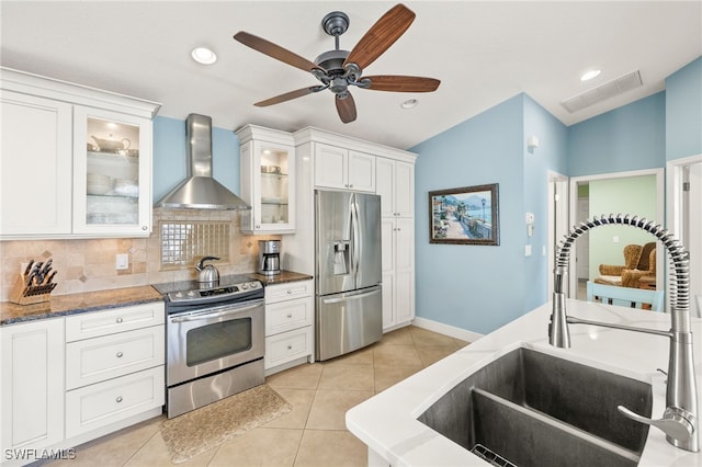 kitchen with visible vents, wall chimney exhaust hood, appliances with stainless steel finishes, a sink, and light tile patterned flooring