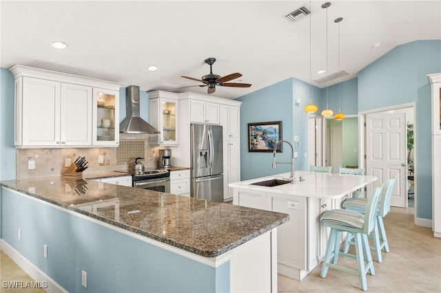 kitchen featuring visible vents, wall chimney exhaust hood, a sink, stainless steel appliances, and backsplash