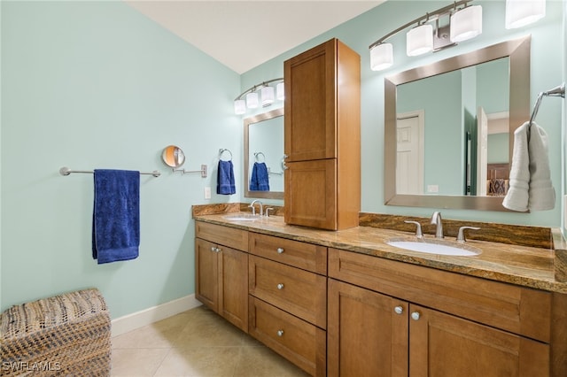 full bathroom with double vanity, baseboards, a sink, and tile patterned floors