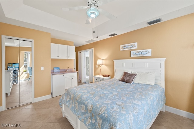 bedroom with a tray ceiling, visible vents, and a sink