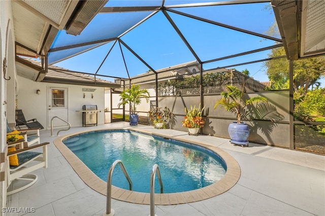 pool with glass enclosure, a patio area, and area for grilling