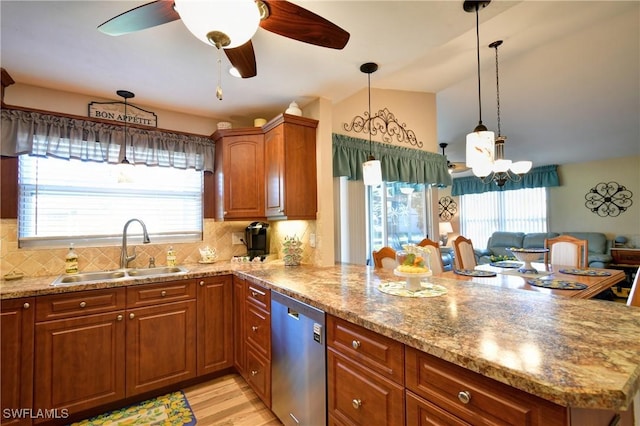 kitchen featuring stainless steel dishwasher, a peninsula, brown cabinetry, and a sink