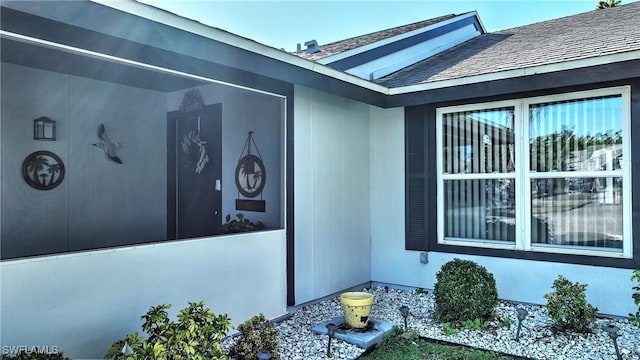 view of exterior entry featuring a shingled roof