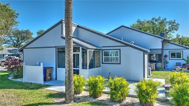 rear view of property with a lawn and a sunroom