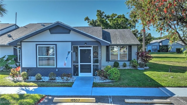 bungalow-style home featuring a front yard, brick siding, and a shingled roof