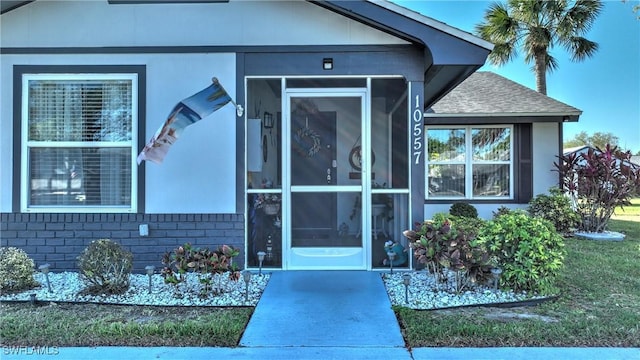 entrance to property with brick siding and roof with shingles