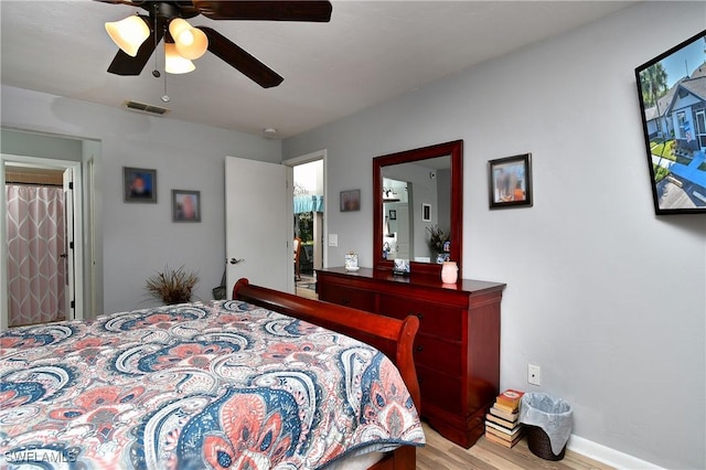 bedroom featuring light wood-style flooring, baseboards, visible vents, and ceiling fan