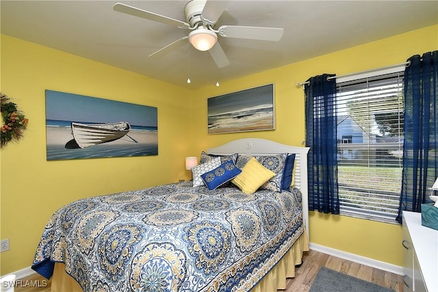 bedroom with a ceiling fan, baseboards, and wood finished floors