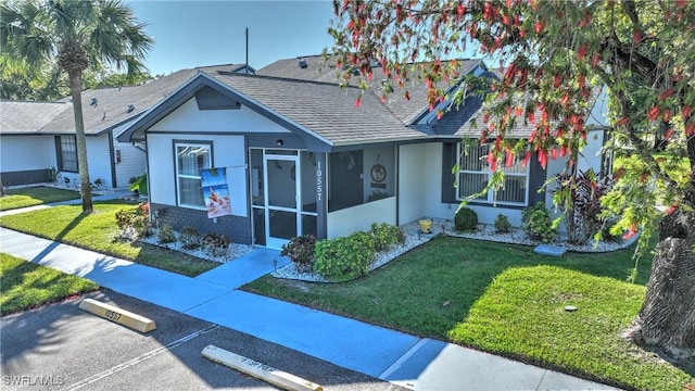 view of front of property featuring stucco siding, a front lawn, and a shingled roof