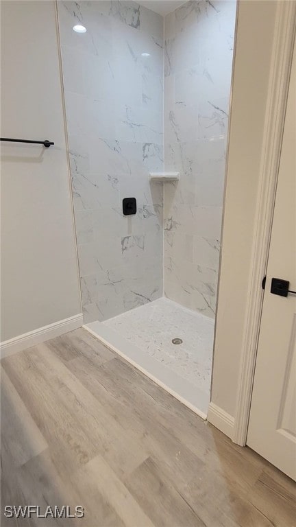 bathroom featuring a stall shower, baseboards, and wood finished floors