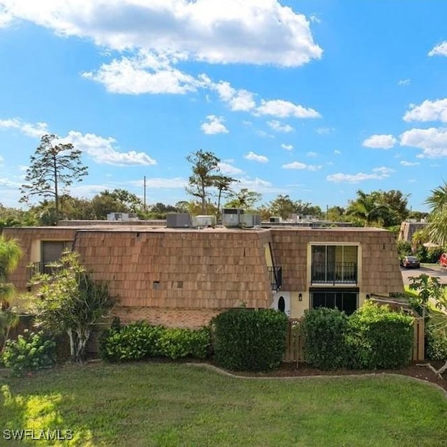 rear view of property featuring mansard roof and a lawn