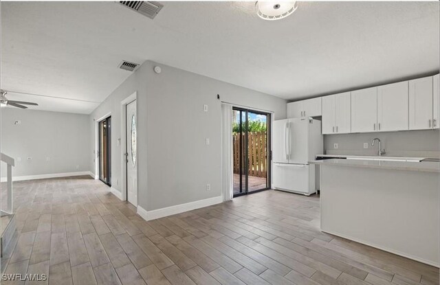 kitchen featuring open floor plan, freestanding refrigerator, light wood finished floors, ceiling fan, and light countertops