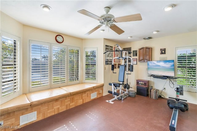 exercise room with baseboards, visible vents, and a ceiling fan