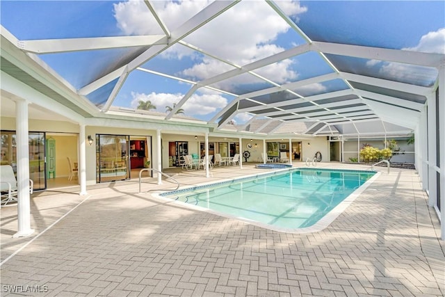 pool with a patio area, glass enclosure, and an in ground hot tub