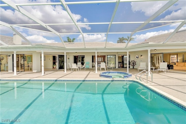 view of pool featuring glass enclosure, a pool with connected hot tub, and a patio