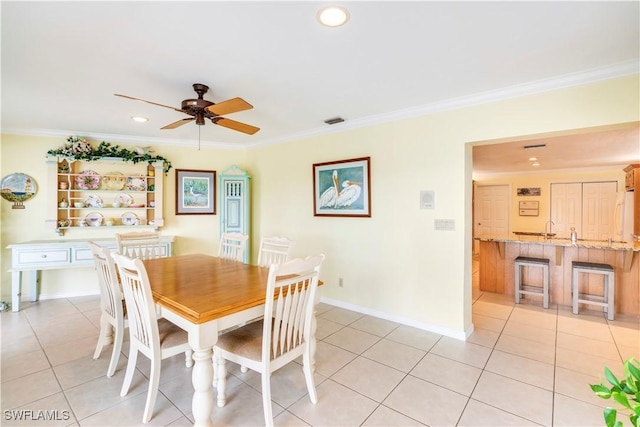 dining area with light tile patterned floors, ceiling fan, ornamental molding, and baseboards