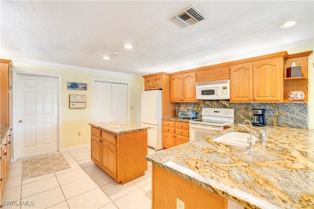 kitchen featuring white appliances, visible vents, a sink, light stone countertops, and backsplash