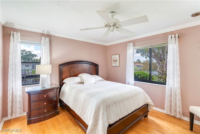 bedroom with baseboards, multiple windows, ornamental molding, and wood finished floors