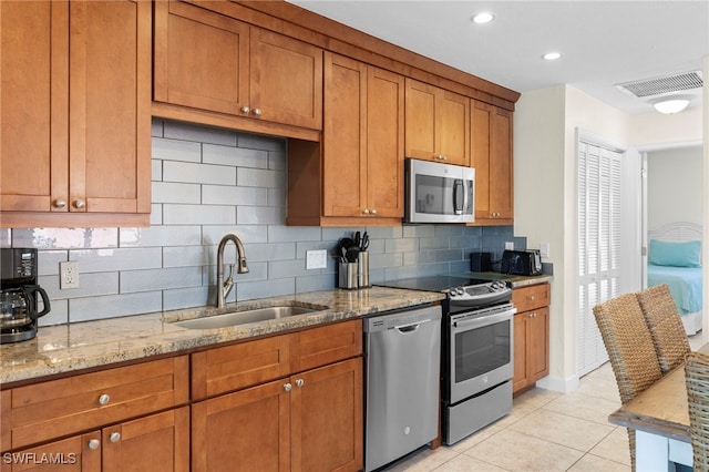 kitchen with a sink, stainless steel appliances, brown cabinets, and visible vents