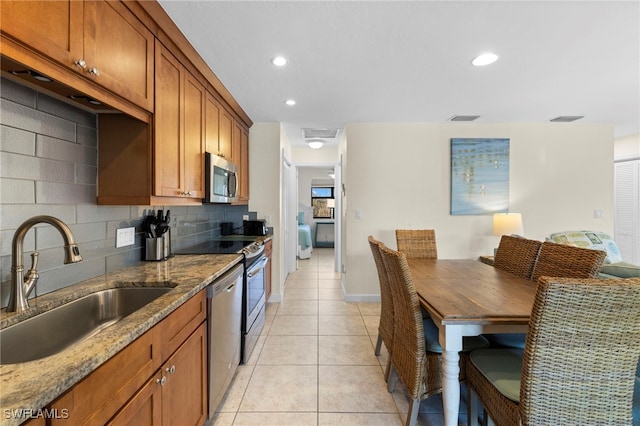 kitchen with visible vents, decorative backsplash, appliances with stainless steel finishes, brown cabinetry, and a sink