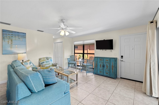 living area with light tile patterned floors, visible vents, baseboards, and ceiling fan