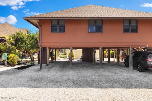 view of front of house featuring a carport, stairway, driveway, and a shingled roof