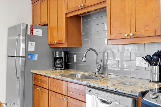 kitchen with light stone counters, tasteful backsplash, appliances with stainless steel finishes, and a sink