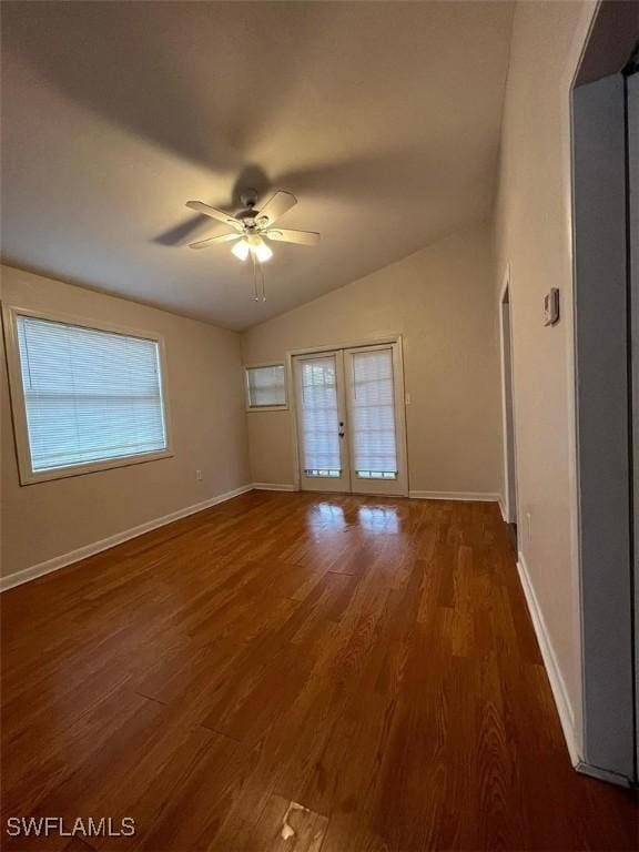 empty room featuring a ceiling fan, wood finished floors, french doors, baseboards, and vaulted ceiling