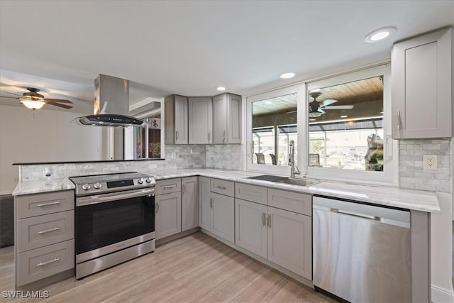 kitchen with ceiling fan, gray cabinetry, a sink, stainless steel appliances, and island range hood