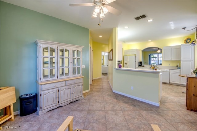 kitchen featuring white appliances, visible vents, ceiling fan, and white cabinetry