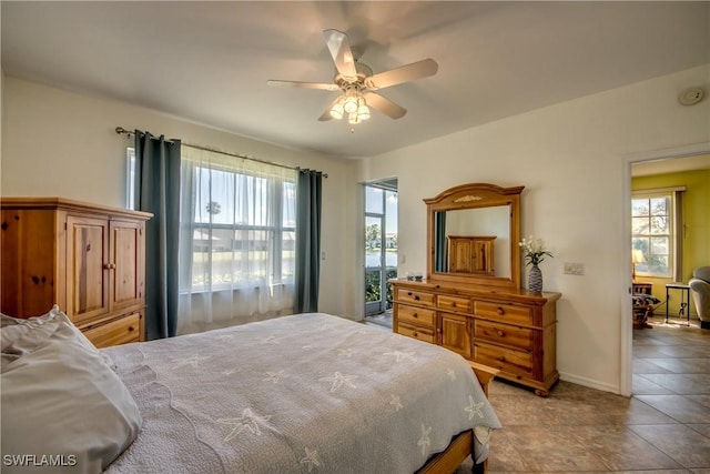 tiled bedroom with multiple windows, ceiling fan, and baseboards