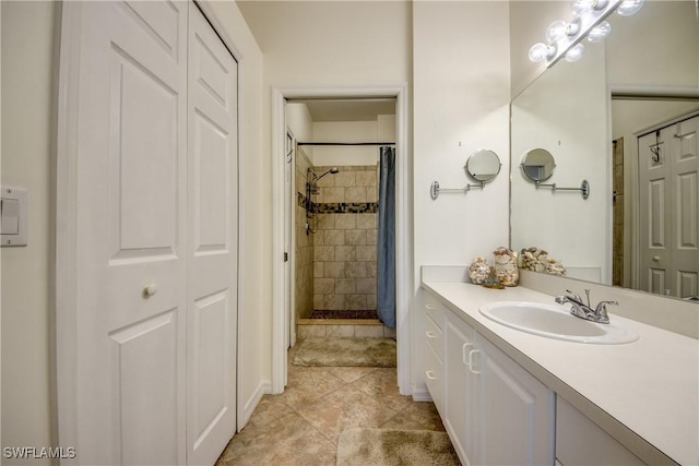 bathroom with a closet, a tile shower, vanity, and tile patterned floors